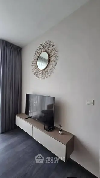 Modern living room with stylish TV setup and decorative mirror, featuring sleek flooring and elegant curtains.