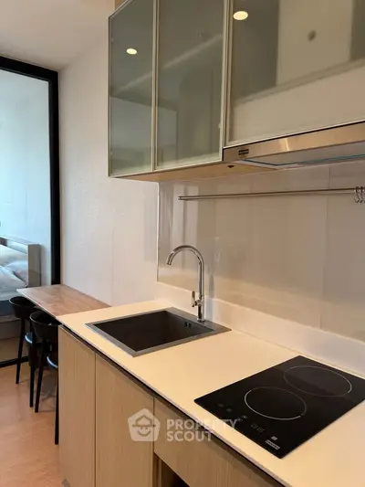 Modern kitchen with sleek design, featuring induction cooktop and stylish cabinetry in a contemporary apartment.