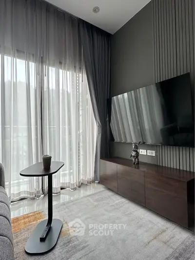 Modern living room with sleek TV setup and floor-to-ceiling windows for natural light.