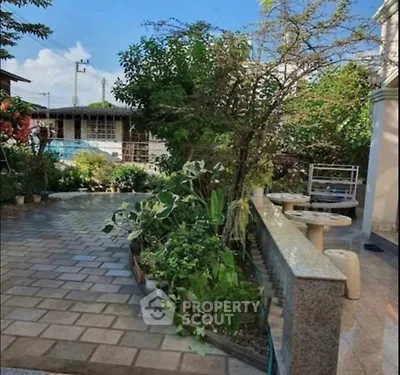 Charming garden area with lush greenery and paved walkway, perfect for outdoor relaxation.