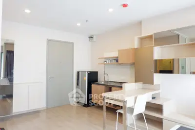 Modern studio apartment with sleek kitchen and dining area, featuring minimalist design and ample natural light.