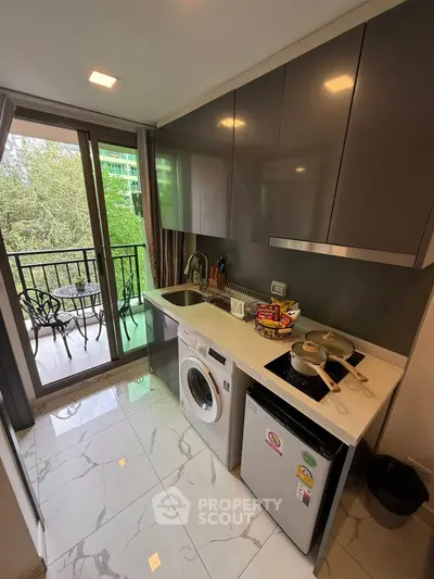 Modern kitchen with sleek cabinets, washing machine, and balcony view, perfect for urban living.