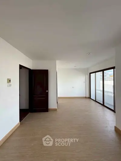 Spacious empty room with large windows and wooden flooring, ideal for customization.