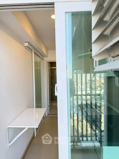 Modern apartment balcony with sliding glass doors and city view, perfect for urban living.