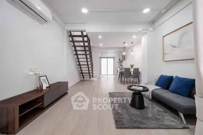 Modern open-plan living room with stylish decor and staircase leading to upper level.