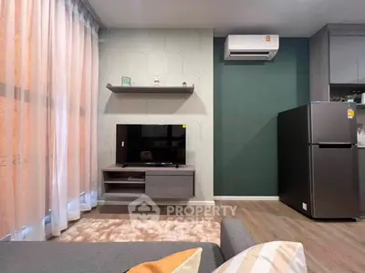 Modern living room with stylish decor, featuring a TV unit, air conditioning, and a sleek refrigerator.