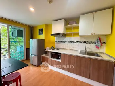 Modern kitchen with vibrant yellow walls, sleek cabinets, and stainless steel appliances.