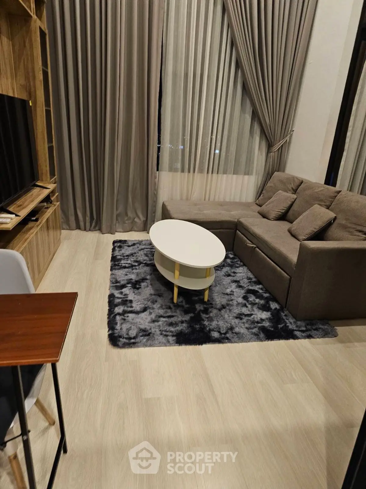 Modern living room with cozy sofa, stylish rug, and elegant curtains in a chic apartment.