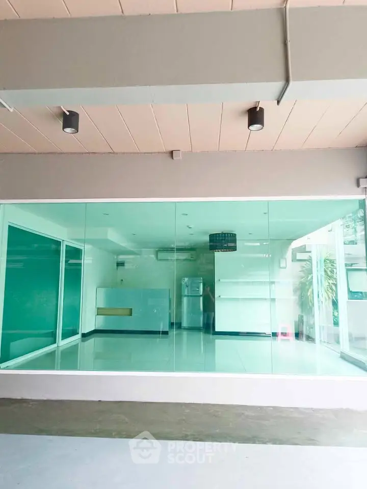 Modern glass-walled room with sleek design and natural light, perfect for versatile use.