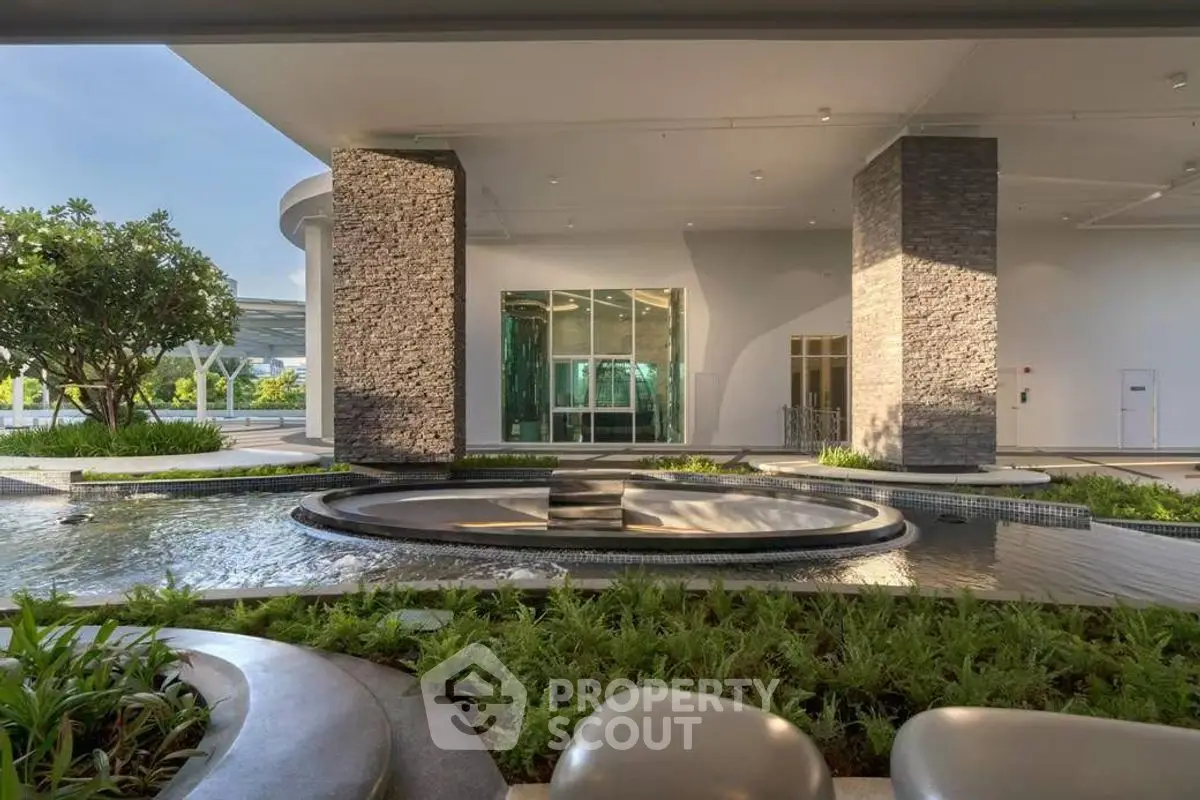 Luxurious building entrance with modern water feature and lush greenery