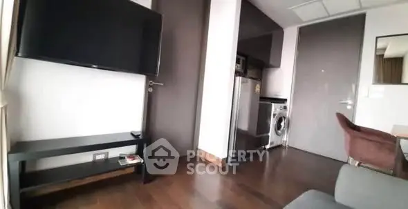 Modern apartment interior with TV, washing machine, and sleek furniture.