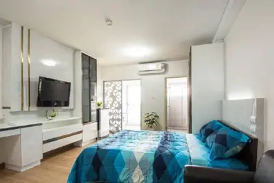Modern bedroom with stylish decor and natural light, featuring a mounted TV and air conditioning.