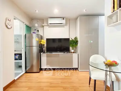 Modern living room with sleek furniture and wooden flooring, featuring a TV and stainless steel fridge.