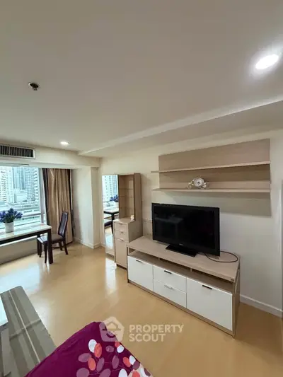 Modern living room with TV and city view, featuring stylish furniture and ample natural light.