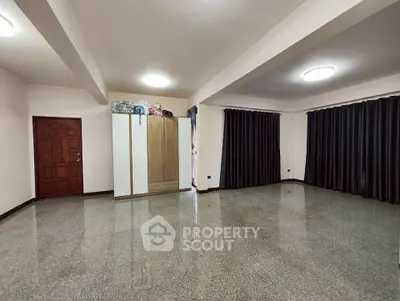 Spacious empty living room with polished floors and dark curtains, ideal for customization.