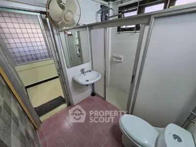 Compact bathroom with pink tiles, shower, and modern fixtures in a cozy apartment.