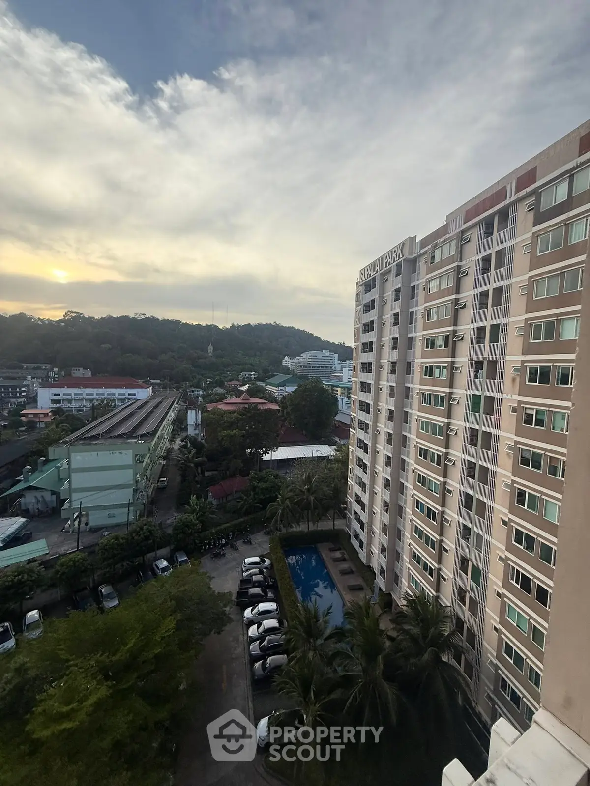 High-rise building with pool and parking, offering scenic views at sunset.
