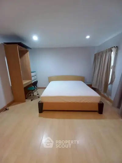 Spacious bedroom with wooden flooring and modern furniture