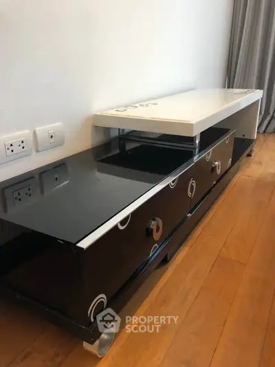 Modern black and white TV stand with sleek design on wooden floor.