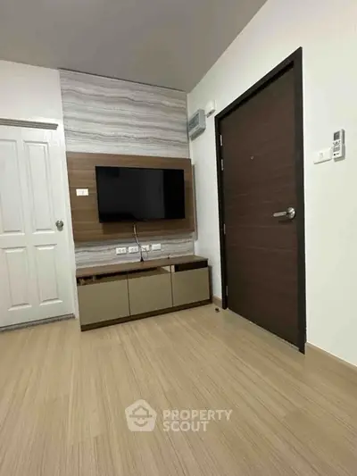 Modern living room with sleek wooden flooring and mounted TV, perfect for cozy evenings.