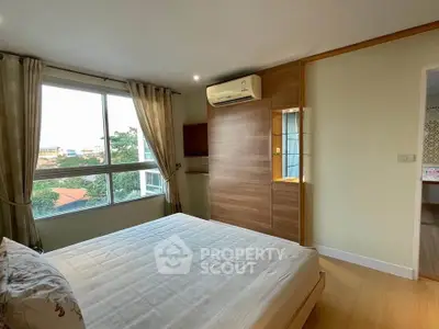 Spacious bedroom with large window and modern air conditioning unit, offering a serene view.
