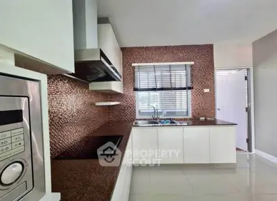Modern kitchen with sleek design and closed layout, featuring a built-in microwave and stylish backsplash.