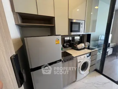 Modern compact kitchen with appliances including fridge, microwave, and washing machine in sleek design.