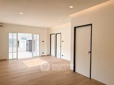 Spacious modern living room with wooden flooring and large windows for natural light.
