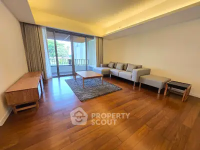 Spacious living room with modern furniture and large windows opening to a balcony with a view.
