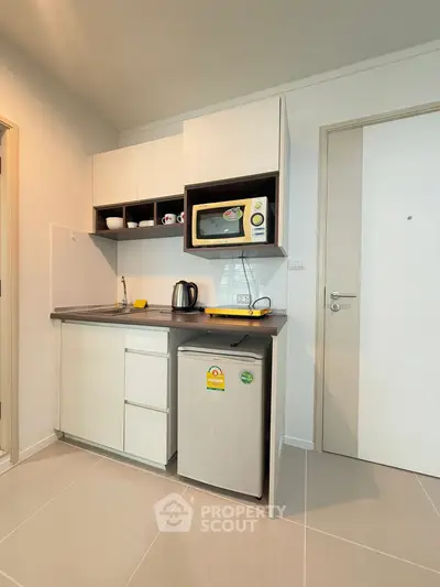 Compact modern kitchen with microwave and mini fridge in cozy apartment.
