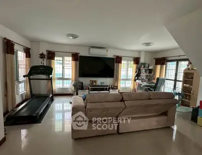 Spacious living room with treadmill and entertainment center, perfect for relaxation and fitness.