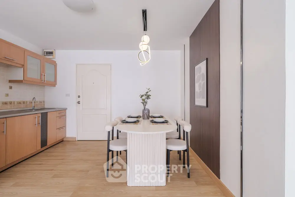 Modern dining area with elegant table and chairs, adjacent to a stylish kitchen with wooden cabinets.