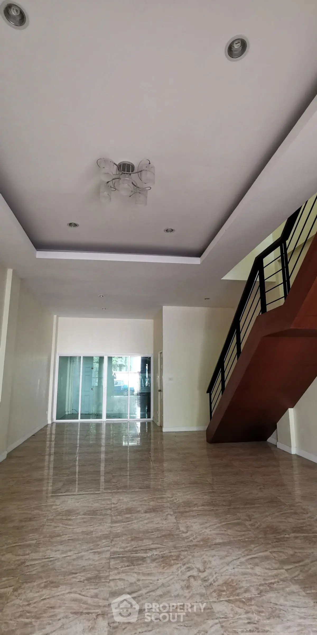 Spacious modern living room with elegant staircase and glossy tiled flooring