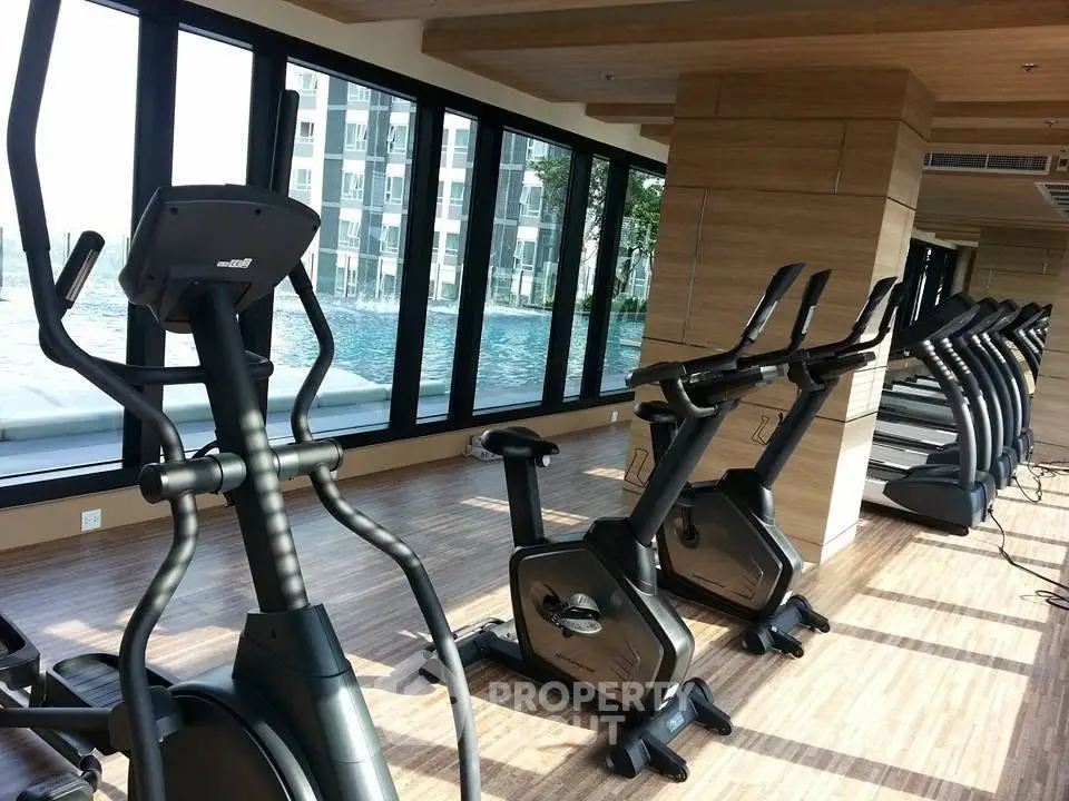 Modern gym with state-of-the-art equipment and pool view in luxury apartment complex.