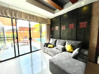 Luxurious living room with plush gray sofa and poolside view, perfect for relaxation and entertainment.