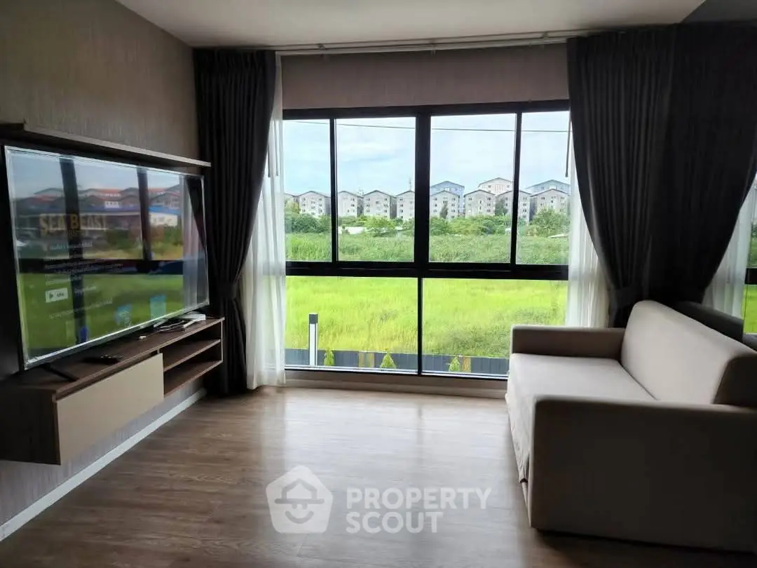 Modern living room with large windows offering scenic views of greenery and distant buildings.