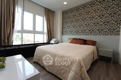 Elegant bedroom with stylish wallpaper and large window for natural light.