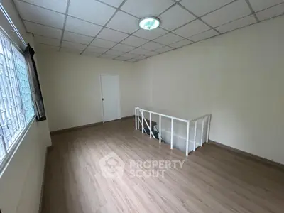 Spacious room with wooden flooring and staircase, ideal for versatile use in modern home.