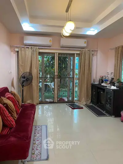Spacious living room with modern decor and garden view, featuring elegant lighting and air conditioning.