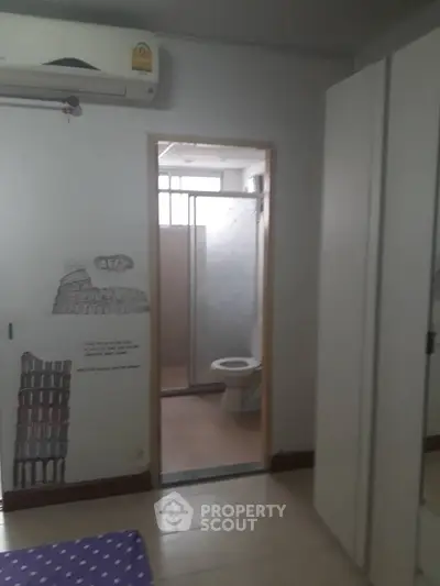 Cozy bedroom with ensuite bathroom and air conditioning in modern apartment.