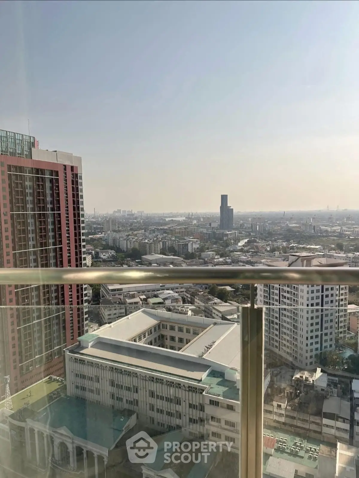 Stunning cityscape view from a high-rise balcony with clear skies and urban skyline.