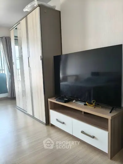 Modern living room with sleek TV stand and wardrobe, featuring natural light and minimalist design.