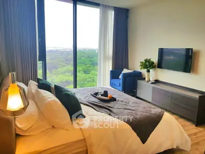 Modern bedroom with large window offering stunning green view, cozy decor, and stylish furnishings.