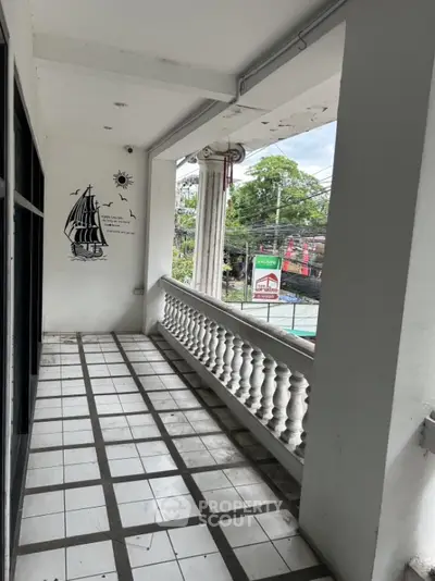 Spacious balcony with decorative wall art and street view, perfect for relaxation.