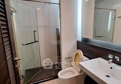 Modern bathroom with glass shower and sleek fixtures in contemporary apartment.