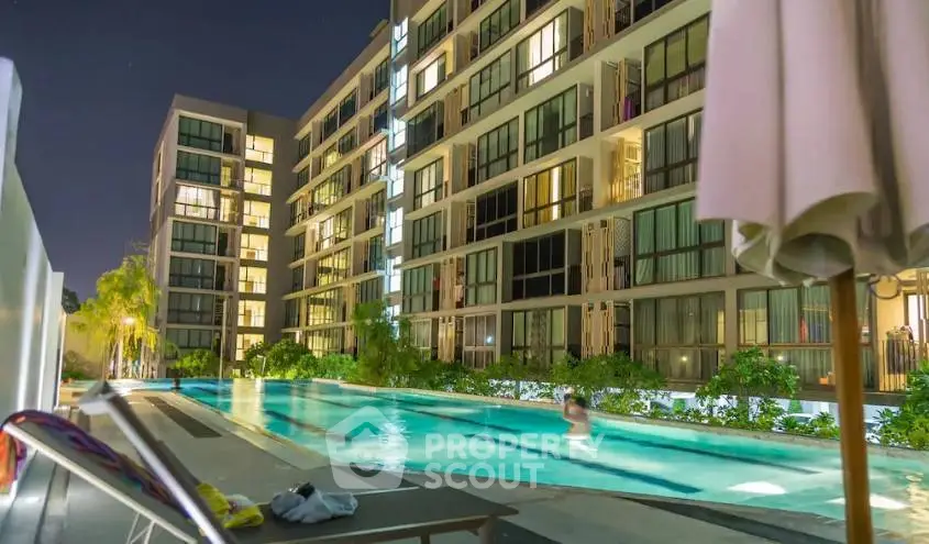 Luxurious apartment complex with illuminated pool and modern architecture at night.
