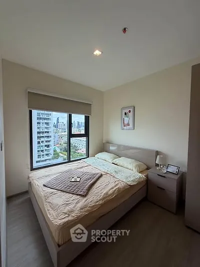 Cozy bedroom with city view, featuring a comfortable bed and modern decor in a high-rise apartment.