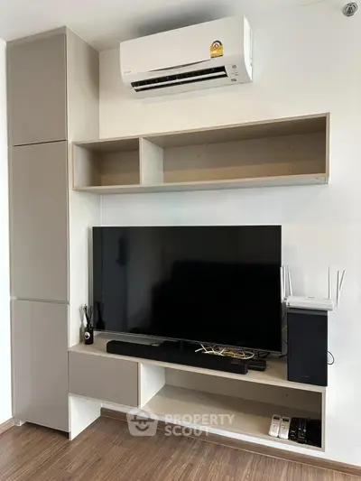 Modern living room with sleek TV setup and air conditioning unit, perfect for entertainment.