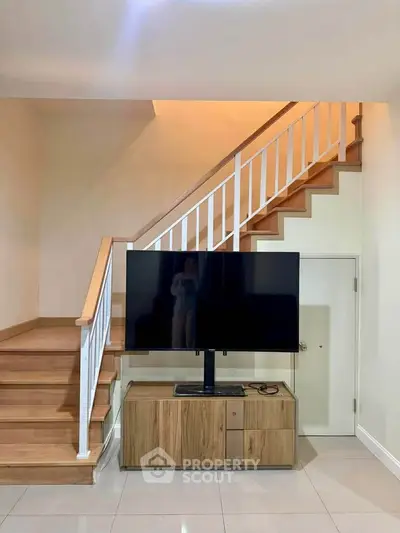 Modern living room with stylish staircase and large TV setup