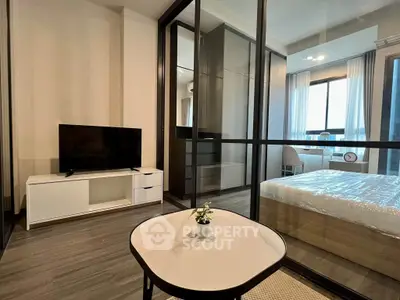 Modern apartment interior with glass partition, featuring a cozy living area and stylish bedroom.